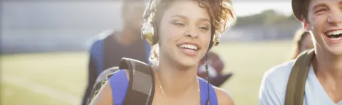 Smiley teenage girl with headphones and backpack.